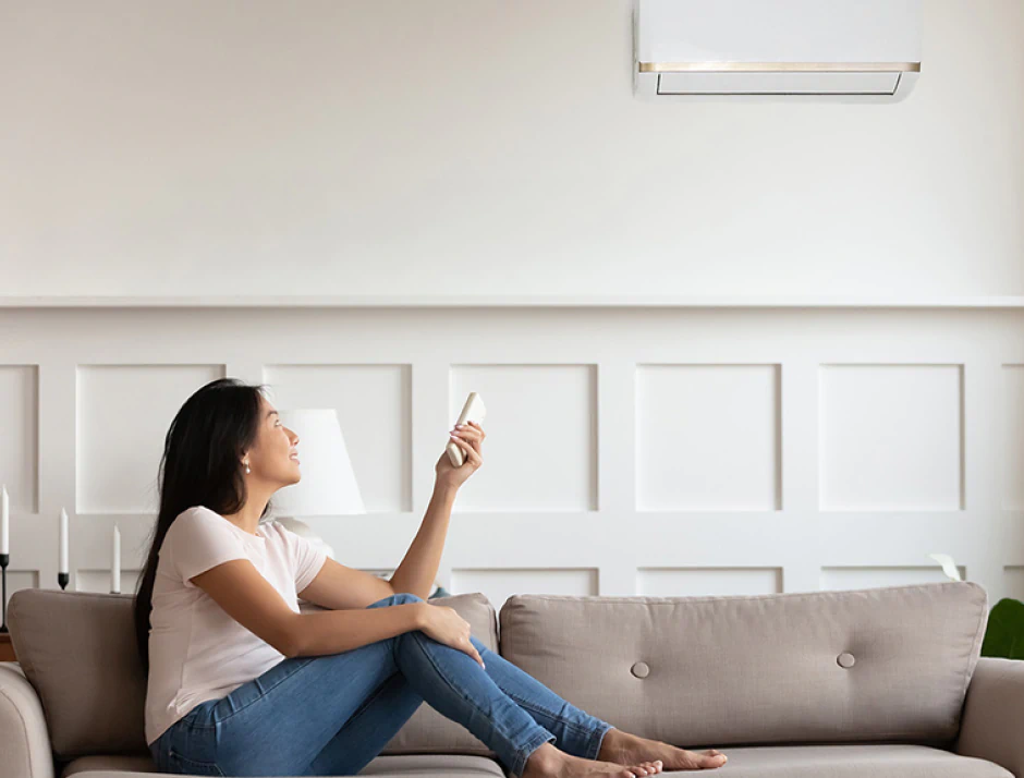 woman on couch turning ac on with remote